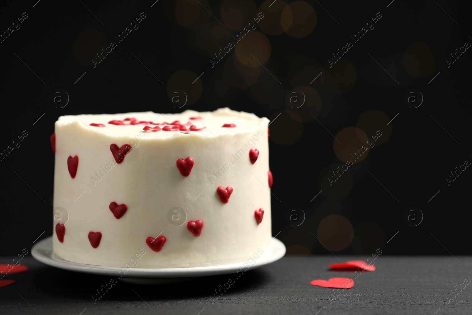 Photo of Bento cake with red cream hearts on black table, space for text. St. Valentine's day surprise