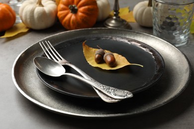 Seasonal table setting with pumpkins and other autumn decor on grey background, closeup