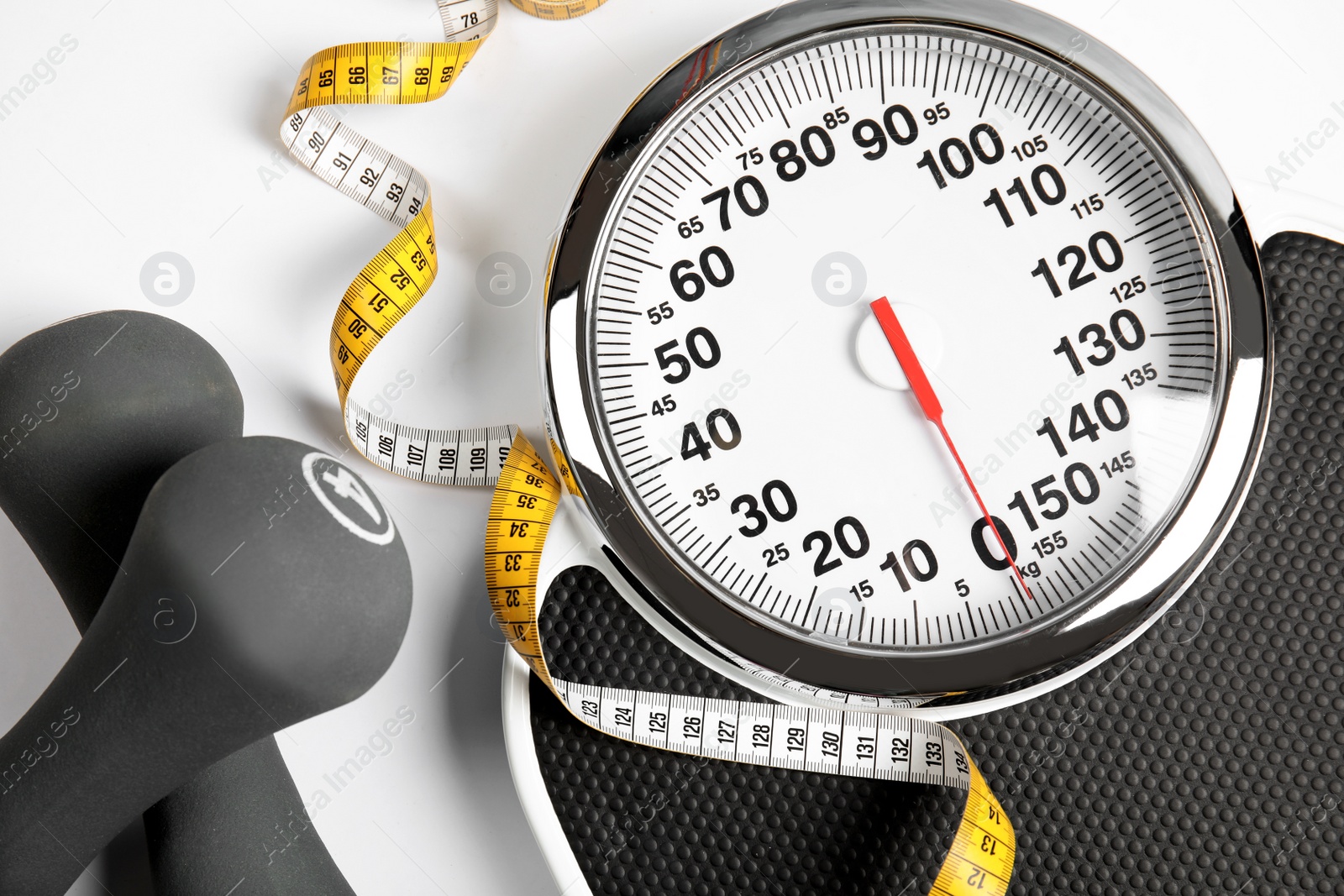 Photo of Modern scales, tape measure and dumbbells on white background