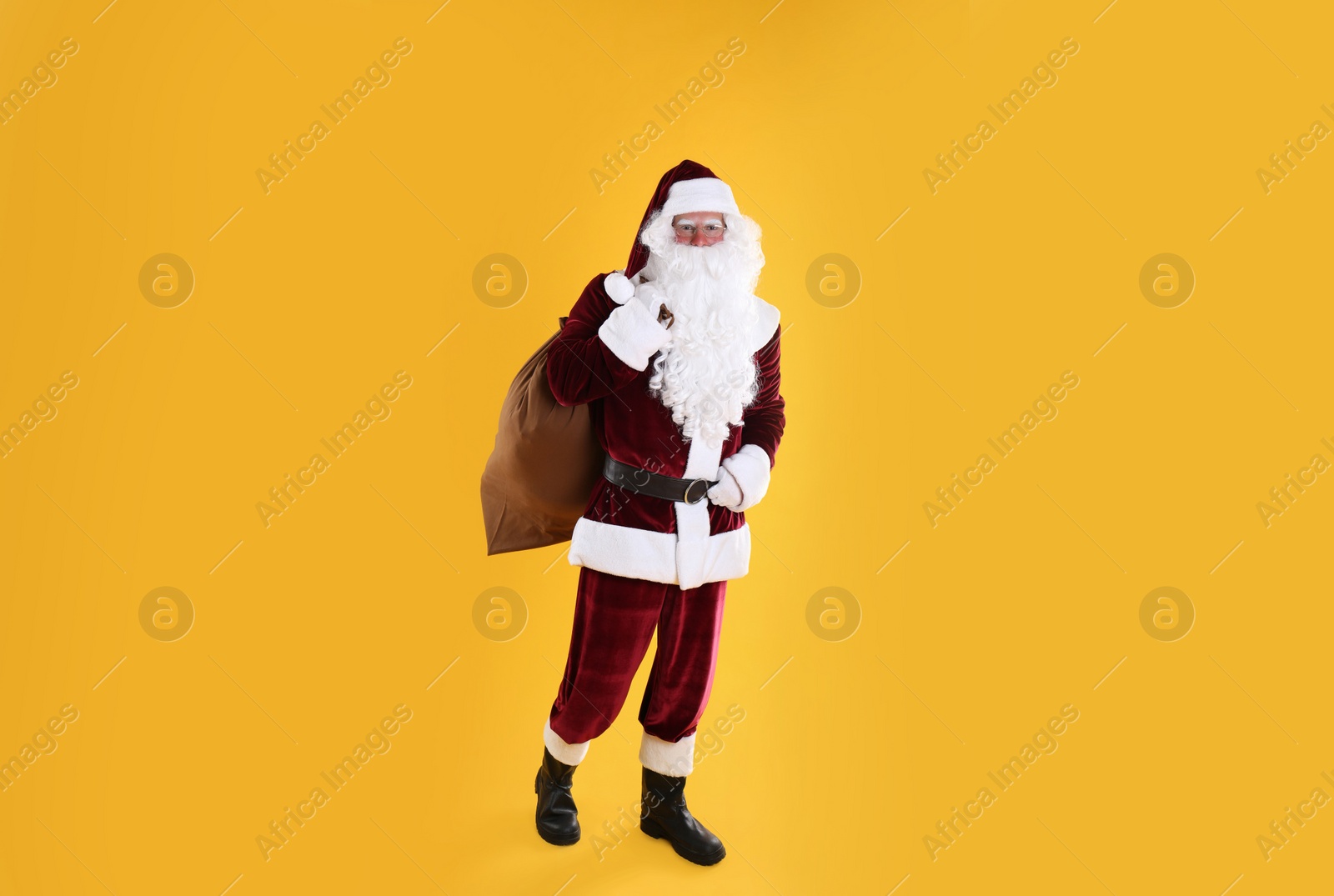 Photo of Full length portrait of Santa Claus with sack on yellow background