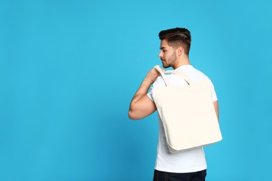 Portrait of young man with eco bag on blue background. Space for text