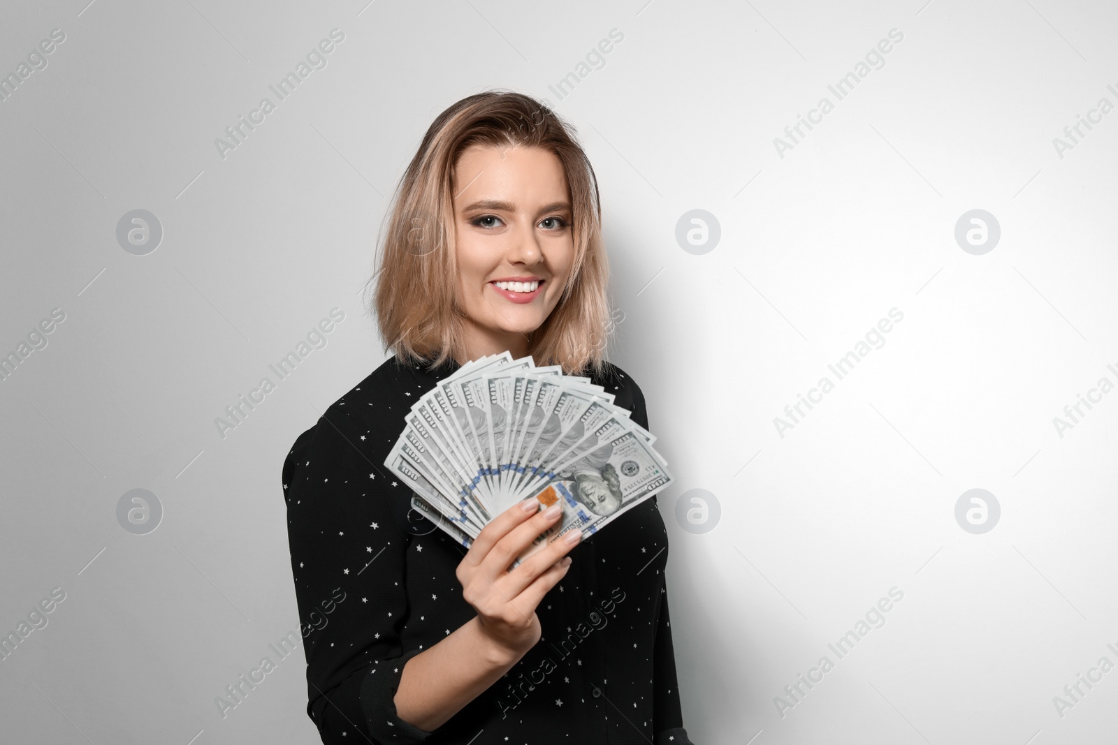 Photo of Portrait of young woman with money fan on light background