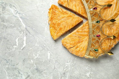 Traditional galette des Rois with decorative crown on grey marble table, flat lay. Space for text