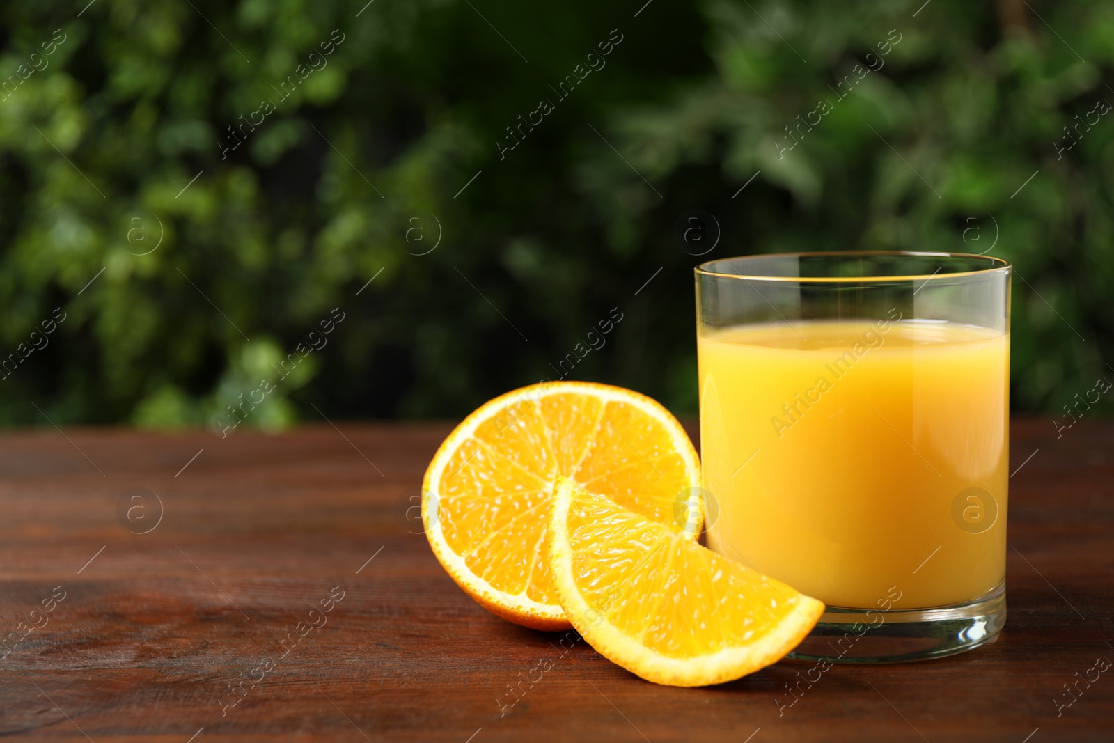 Photo of Glass of orange juice and fresh fruits on wooden table. Space for text