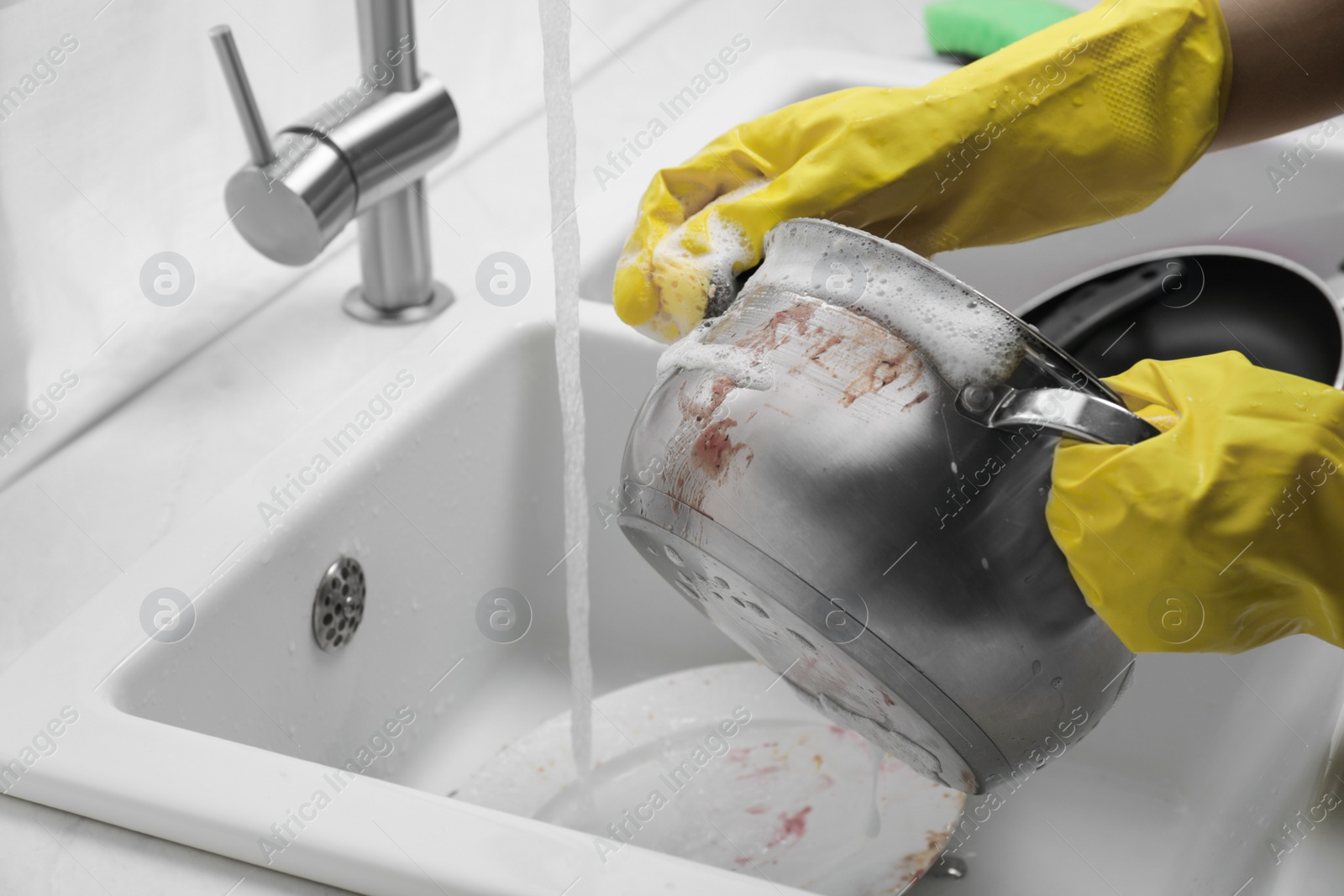 Photo of Woman washing dirty dishes in kitchen sink, closeup