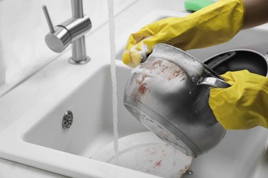 Woman washing dirty dishes in kitchen sink, closeup