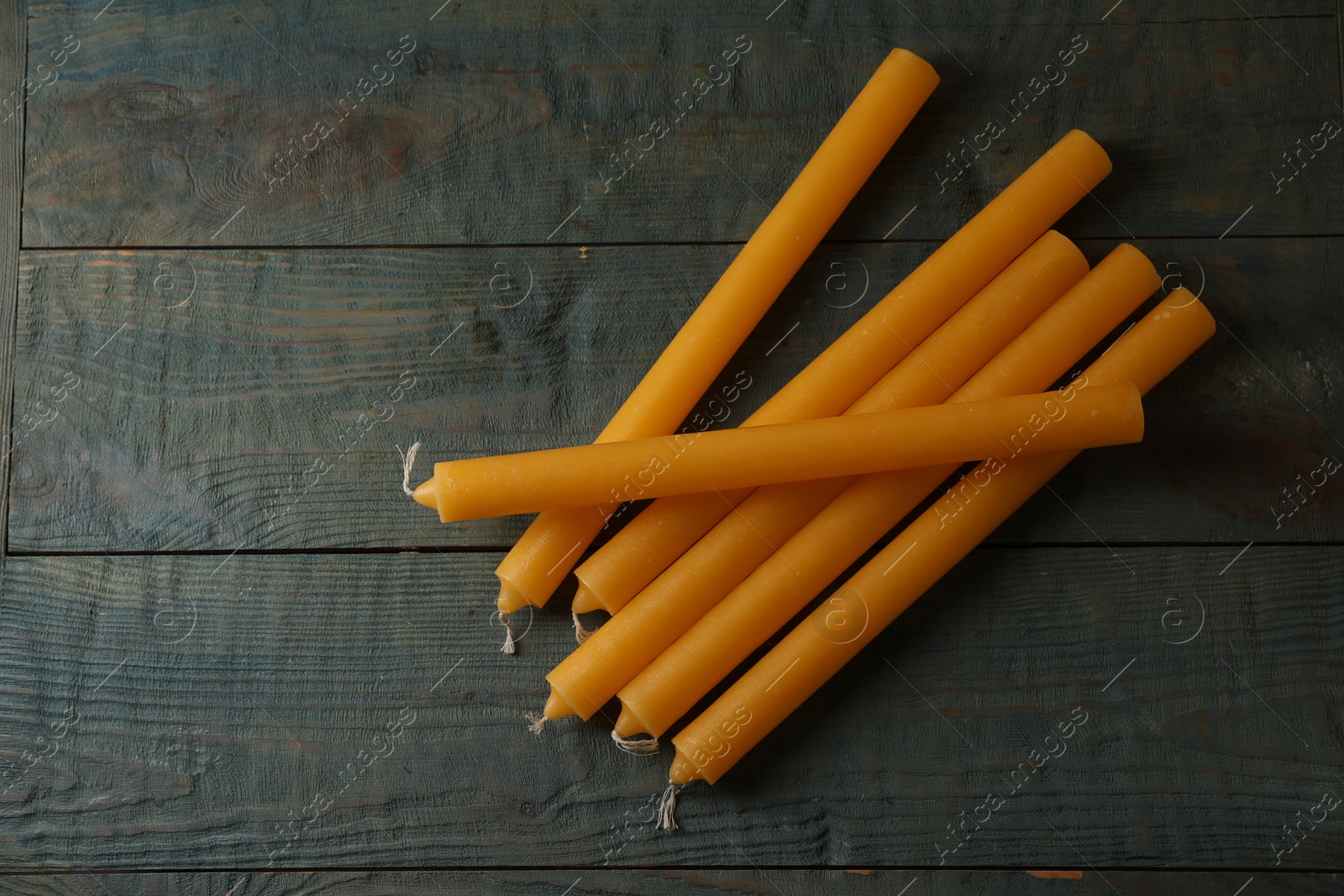 Photo of Many church wax candles on old wooden table, flat lay