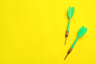 Photo of Green dart arrows on yellow background, flat lay with space for text