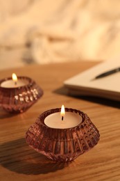 Photo of Burning candles in beautiful glass holders on wooden table indoors