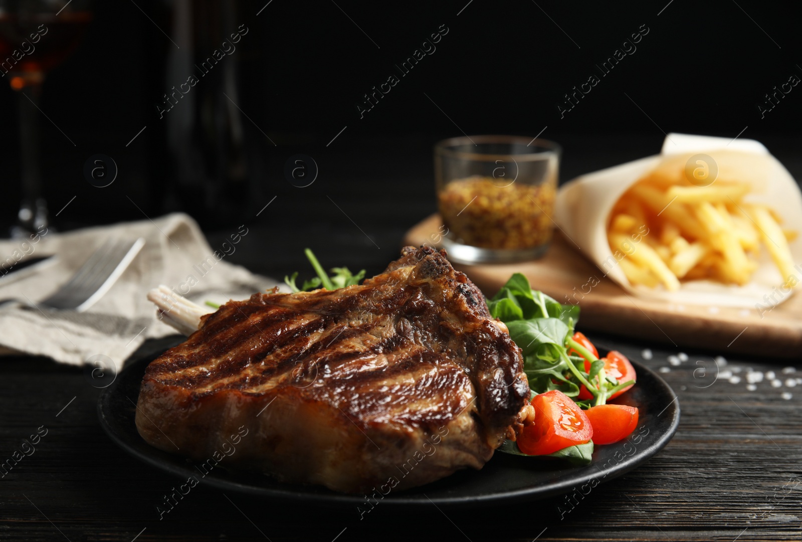 Photo of Tasty grilled beef steak with salad on black wooden table