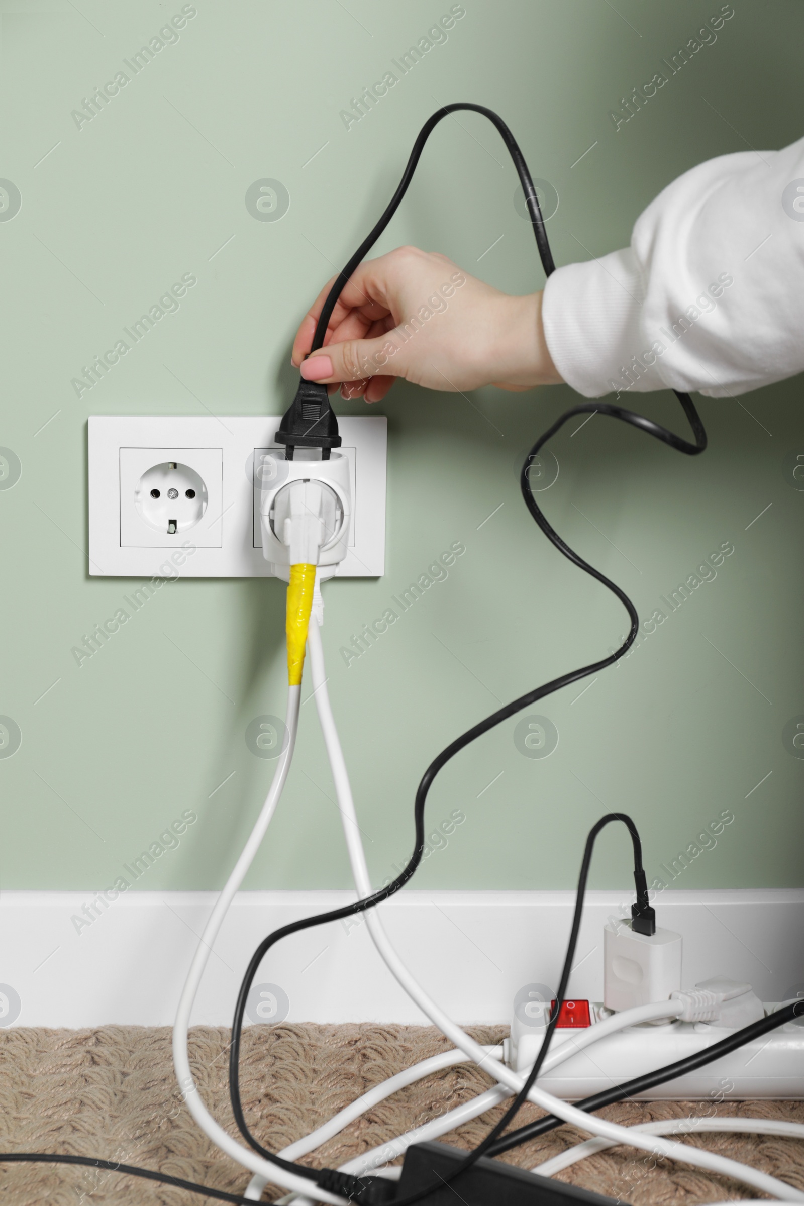 Photo of Woman putting plug into socket indoors, closeup