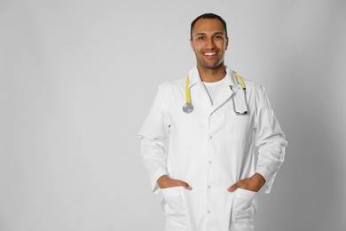 Photo of Doctor or medical assistant (male nurse) in uniform with stethoscope on light grey background. Space for text