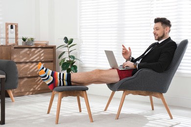 Businessman in underwear pretending to wear formal clothes during video call at home