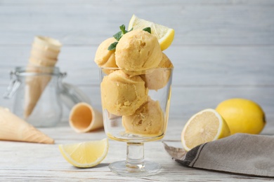 Photo of Yummy lemon ice cream served on white wooden table
