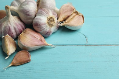Photo of Fresh garlic bulbs and cloves on light blue wooden table, space for text. Organic product