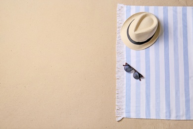 Photo of Straw hat, sunglasses, blanket and space for text on beach sand, top view. Summer vacation