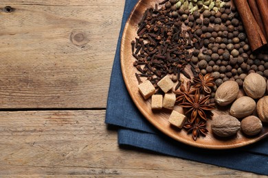 Different spices and nuts on wooden table, top view. Space for text