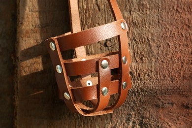 Photo of Brown dog muzzle hanging near wooden fence, closeup