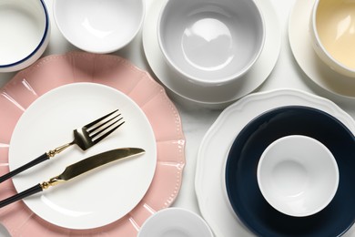 Beautiful ceramic dishware and cutlery on white table, flat lay