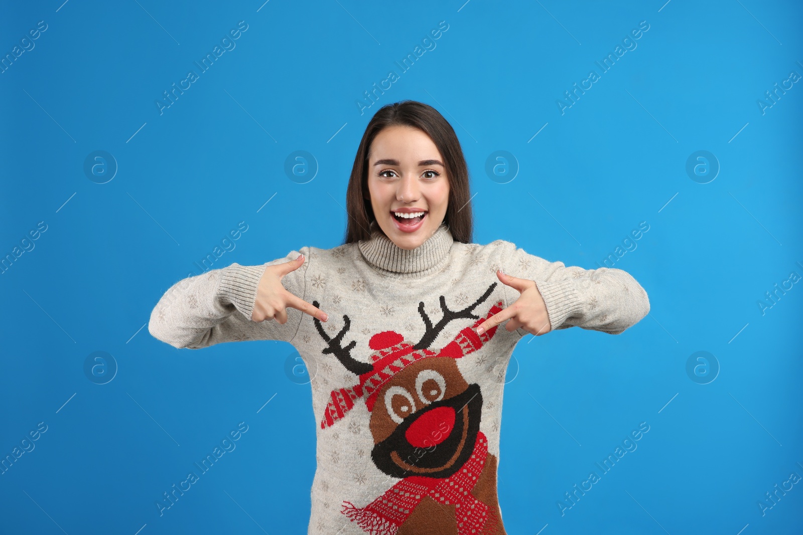 Photo of Young woman in Christmas sweater on blue background