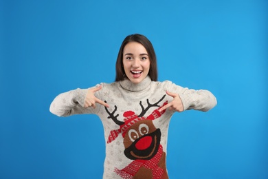 Young woman in Christmas sweater on blue background