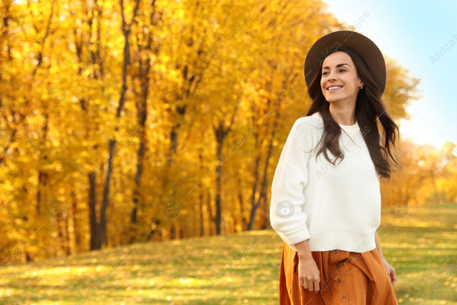 Photo of Beautiful happy woman wearing hat walking in autumn park