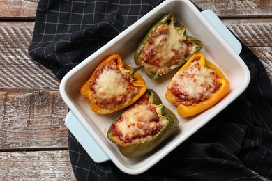 Photo of Tasty stuffed peppers in dish on wooden table, top view