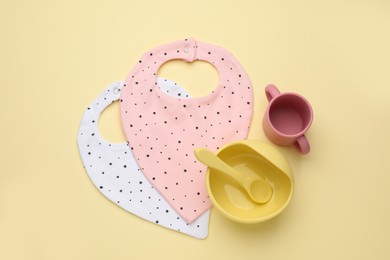 Photo of Flat lay composition with baby feeding accessories and bibs on yellow background