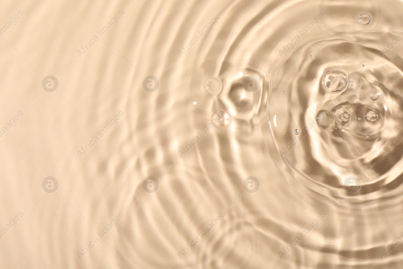 Photo of Closeup view of water with rippled surface on beige background