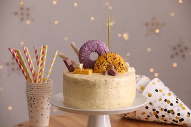 Photo of Delicious cake decorated with sweets and festive items on table