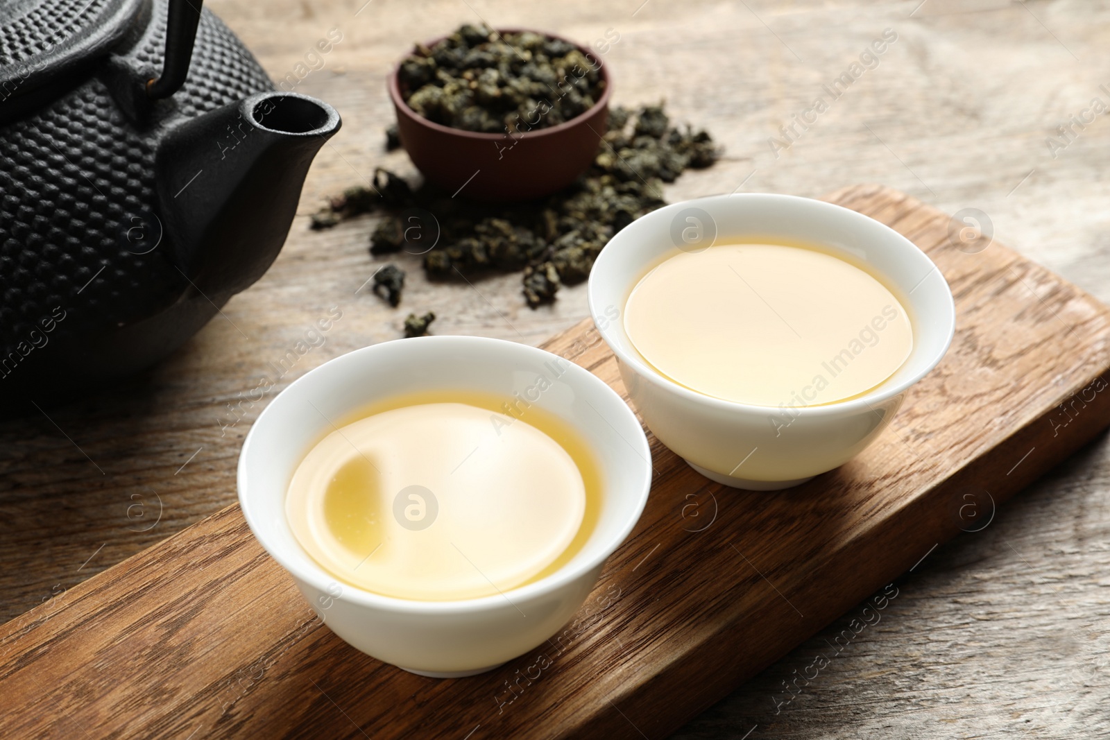 Photo of Cups and teapot of Tie Guan Yin oolong on wooden table