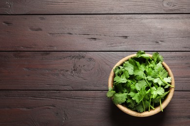 Photo of Fresh aromatic cilantro on wooden table, top view. Space for text