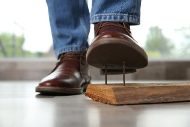 Careless man stepping on nails in wooden plank, closeup