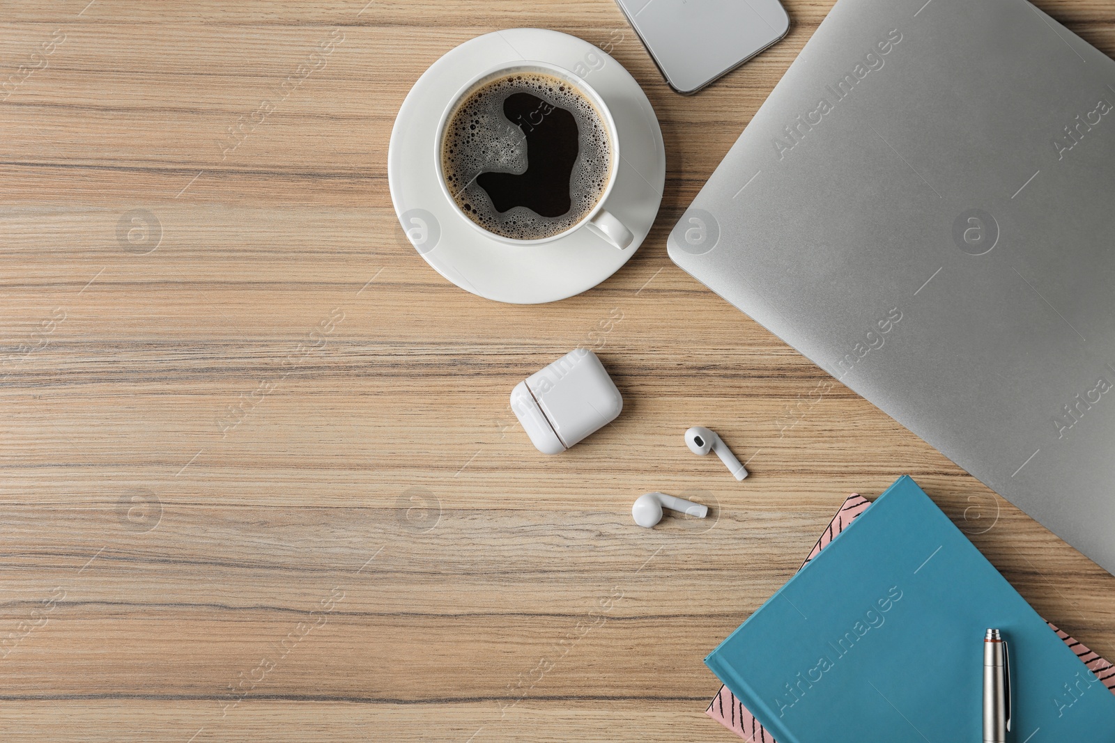 Photo of Flat lay composition with wireless earphones and laptop on wooden table. Space for text