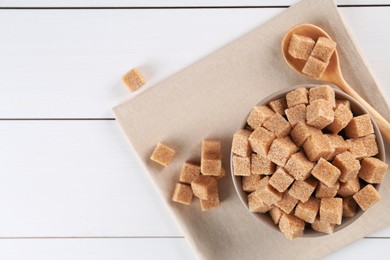 Photo of Brown sugar cubes on white wooden table, flat lay. Space for text