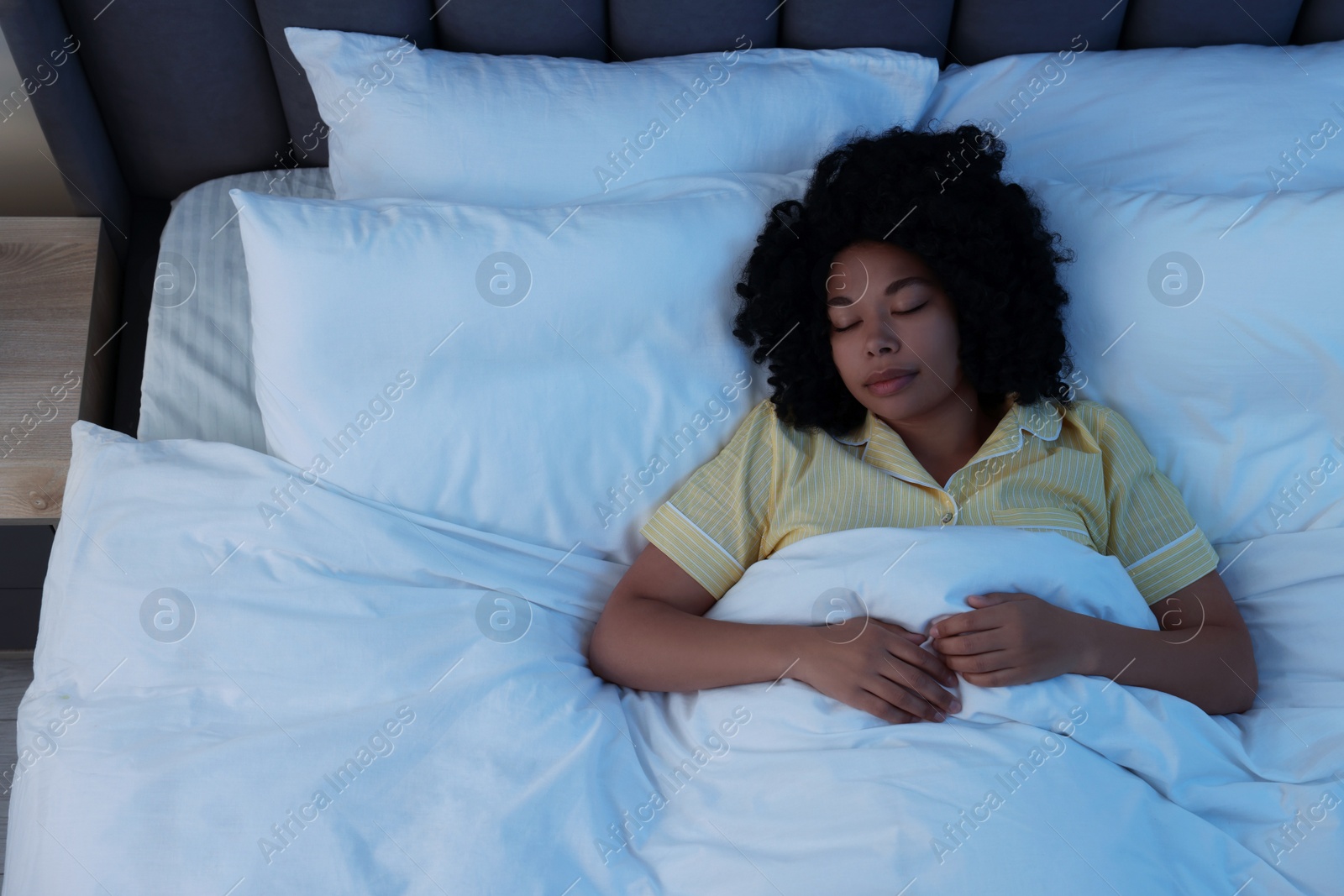 Photo of Young woman sleeping in soft bed at night, above view