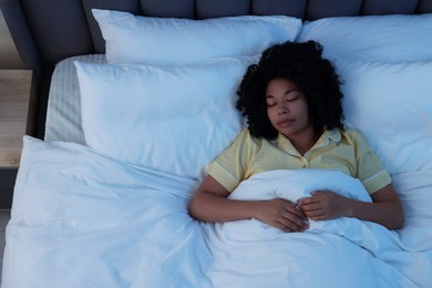 Young woman sleeping in soft bed at night, above view