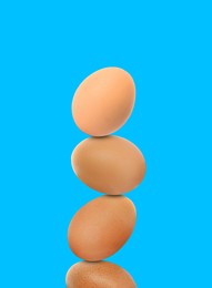 Image of Stacked fresh chicken eggs against light blue background