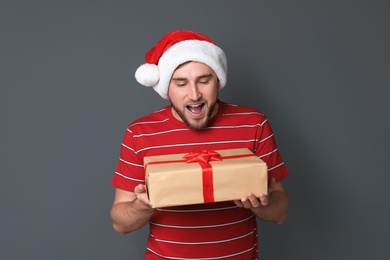 Photo of Young man with Christmas gift on grey background