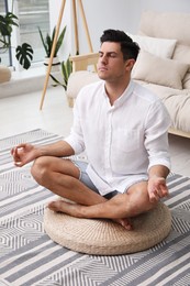 Photo of Man meditating on wicker mat at home