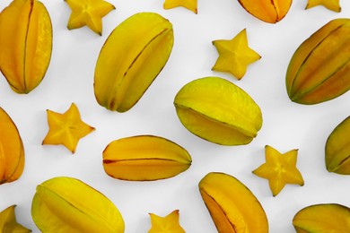 Delicious cut and whole carambolas on white background, top view