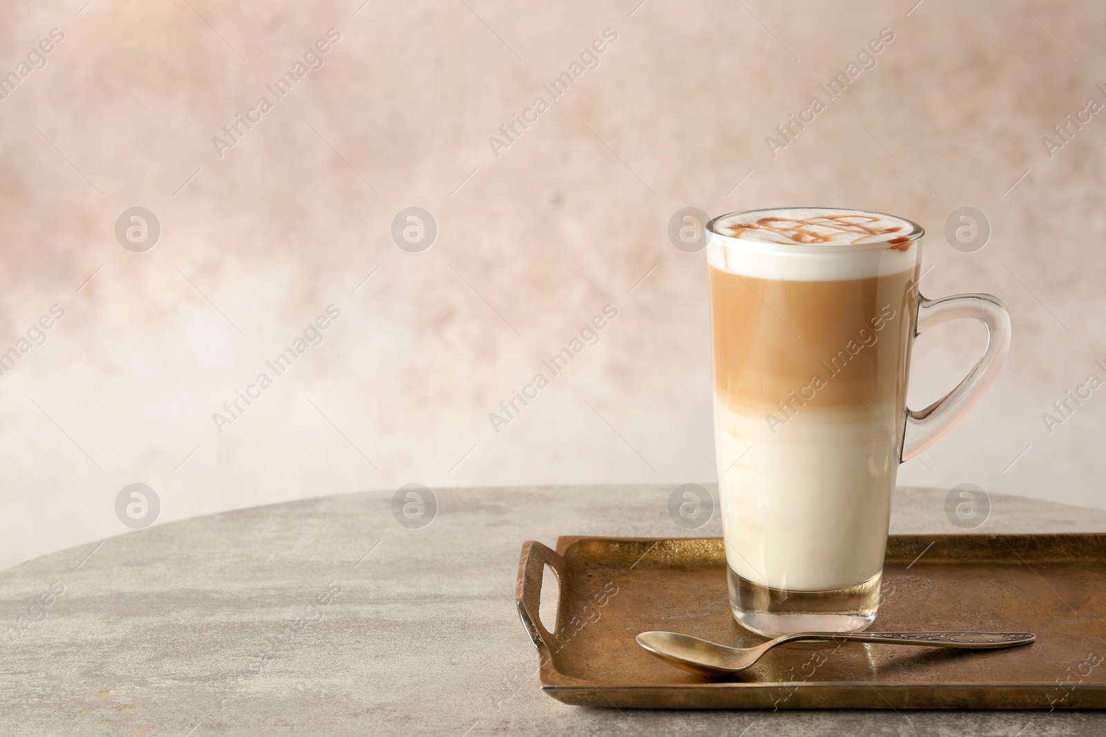 Photo of Tray with glass cup of caramel macchiato and syrup on table against color background. Space for text