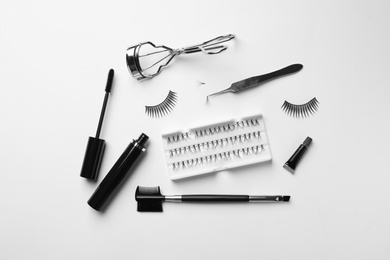 Photo of Composition with false eyelashes and tools on white background, top view