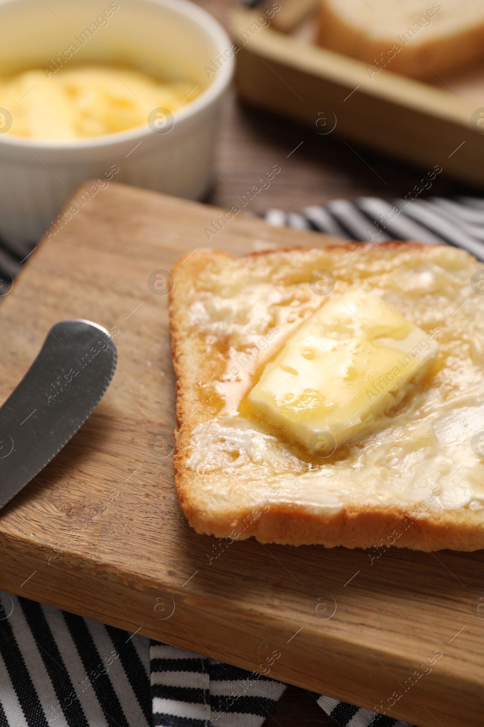 Photo of Melting butter, toast and knife on table, closeup