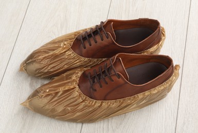 Men`s shoes in shoe covers on light wooden floor