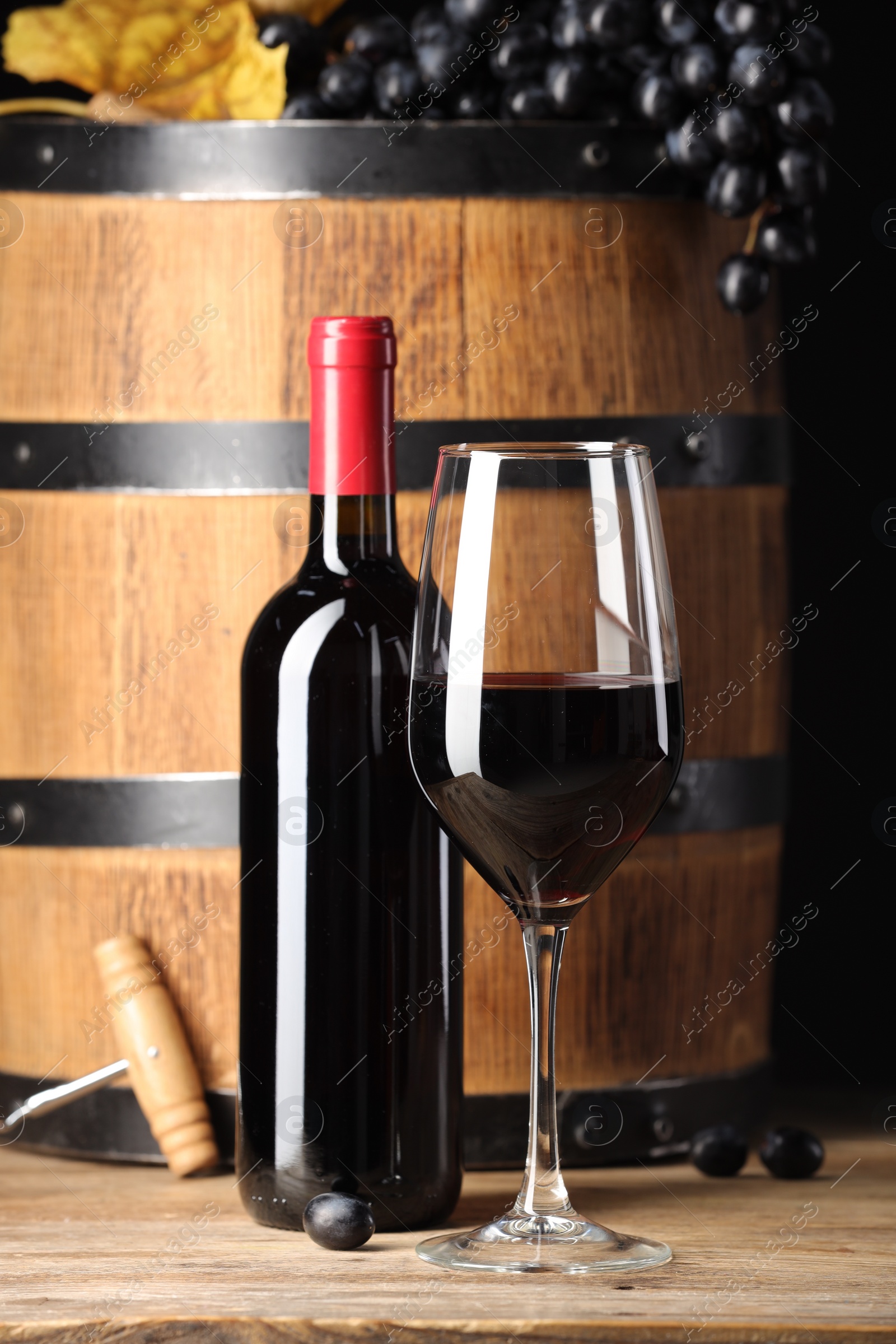 Photo of Delicious wine, wooden barrel and ripe grapes on table