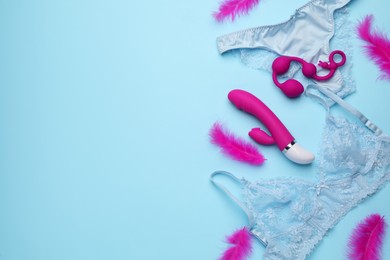 Photo of Sex toys, feathers and lingerie on light blue background, flat lay. Space for text