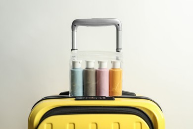 Photo of Cosmetic travel kit in plastic bag on suitcase against light background