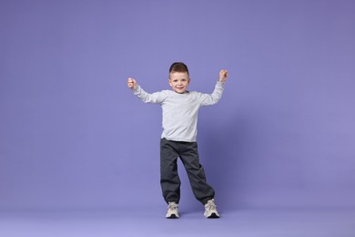 Happy little boy dancing on violet background