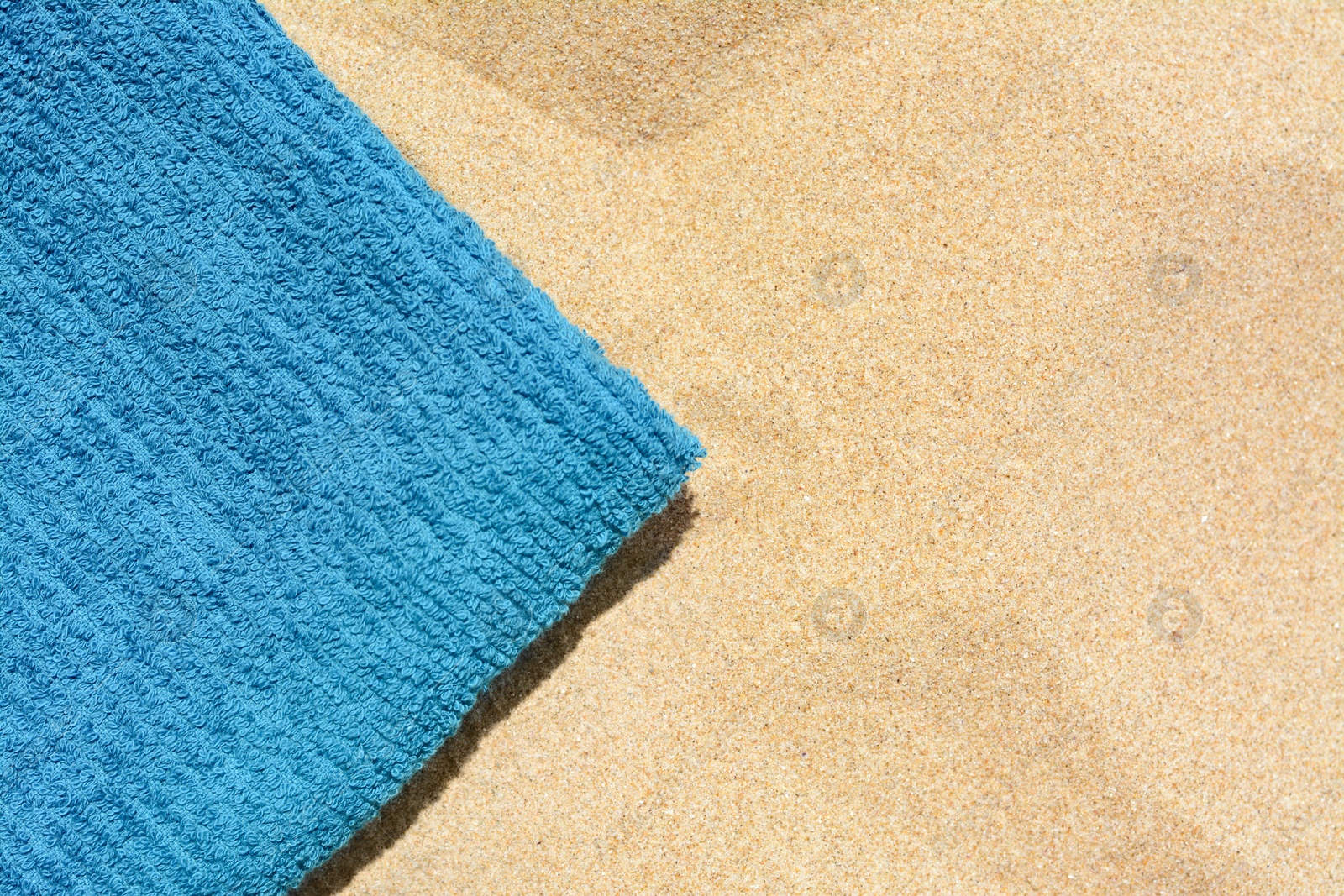 Photo of Soft blue beach towel on sand, top view. Space for text